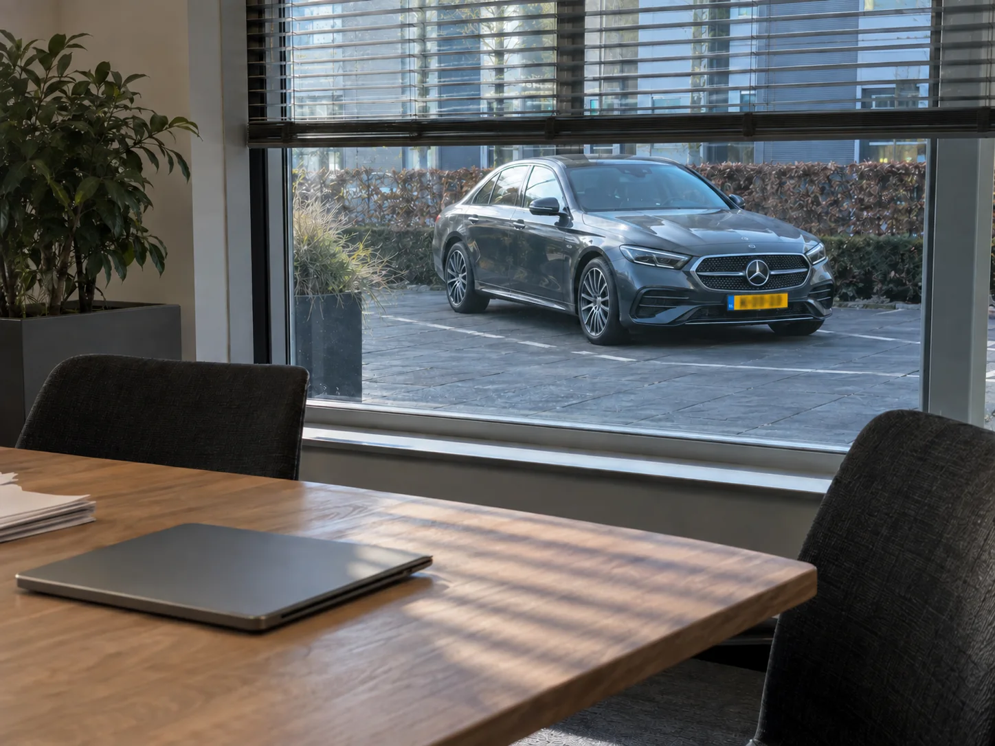 Zakelijke adviesruimte met een Mercedes-Benz E-Klasse zichtbaar door het raam.